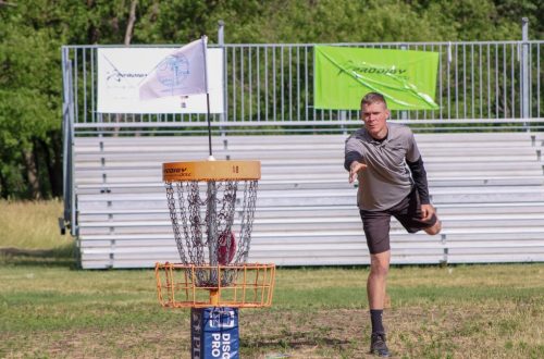A man throws a disc towards the basket during a disc golf tournament in Clearwater, MN.