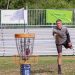 A man throws a disc towards the basket during a disc golf tournament in Clearwater, MN.