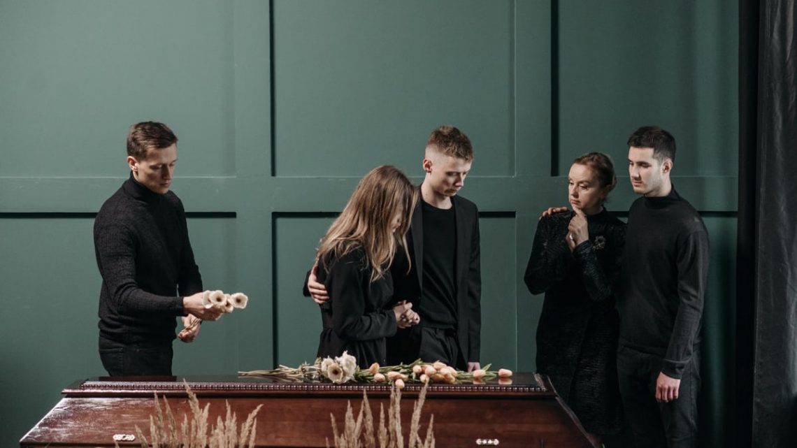 Family mourns together in solemnity at a funeral indoors.