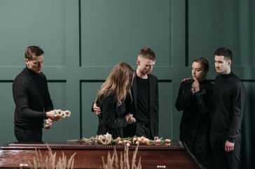 Family mourns together in solemnity at a funeral indoors.