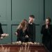 Family mourns together in solemnity at a funeral indoors.