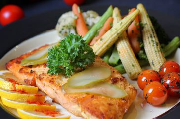 A beautifully plated salmon dish with fresh vegetables and lemon slices, perfect for a gourmet meal.